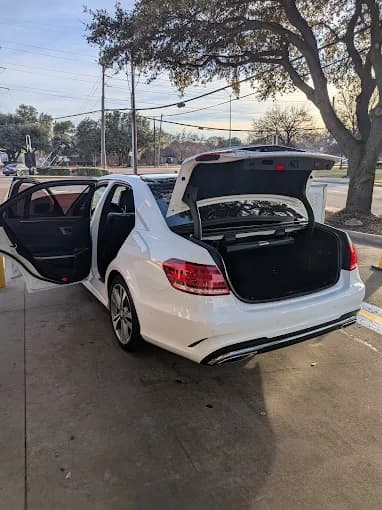 A freshly detailed white sedan with its doors and trunk open at Big Lou's in North Dallas