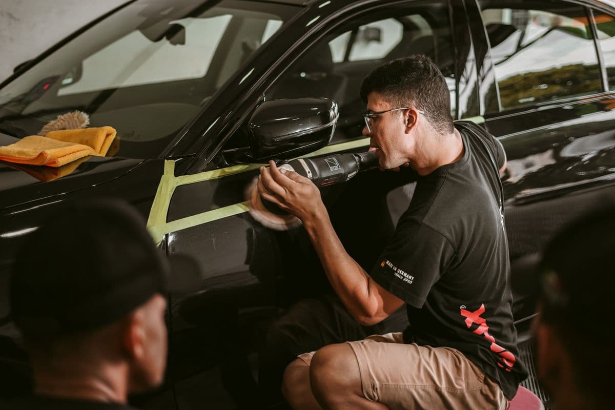 A detailer polishing a black car's paint