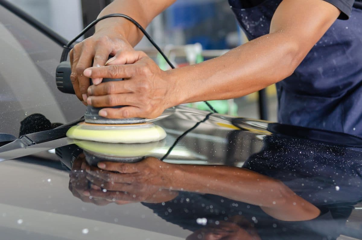 A machine polisher buffing a car hood to a high shine